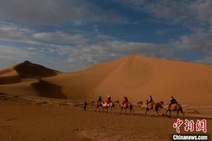 图为甘肃省敦煌市鸣沙山月牙泉景区内,游客沐浴着晨光,欣赏大漠风光,仿佛置身画卷当中。 张晓亮 摄 古郡敦煌大漠晨光引客“画中游”
